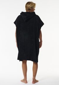 Poncho nero con cappuccio realizzato in morbido tessuto spugna, caratterizzato da maniche corte e una vestibilità ampia, con una texture liscia e una superficie uniforme.
