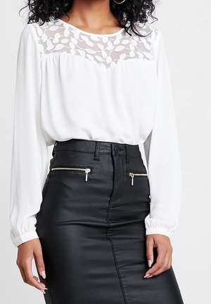 White long-sleeve blouse with sheer floral yoke paired with high-waisted black leather skirt featuring front zipper pockets.