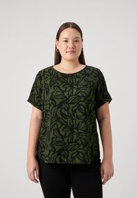 Grön kortärmad topp med svart bladmönster, rund halsringning, avslappnad passform, textil med struktur, kombinerad med svarta byxor.