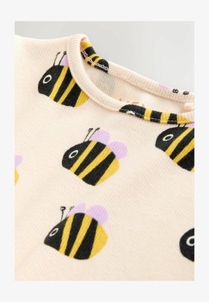 Geribd katoenen top in lichtroze met zwarte en gele bijenpatronen. Heeft een ronde halslijn en lila accenten op de bijenvleugels.