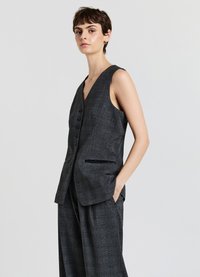 Gilet grigio senza maniche con scollatura a V profonda, sei bottoni frontali e tasche laterali, abbinato a pantaloni larghi coordinati.