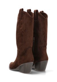 Botas de vaquero de ante marrón con tacones apilados de altura media y costuras decorativas en las cañas, con tirantes para calzar y cremalleras laterales.