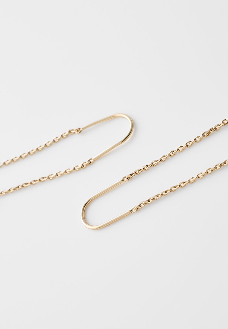Chaîne couleur or avec un motif en maillons et un crochet en forme de U courbé à chaque extrémité, présentant une texture lisse et une finition brillante.
