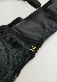Čierny čipkovaný bralet s priesvitnými panelmi a nastaviteľnými ramienkami, s malým zlatým akcentom "Z" na boku.