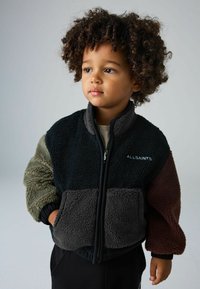 Daugiaspalvė froto striukė su užtrauktuku priekyje, turinti juodus, pilkus, alyvinius ir višninio atspalvius, tekstūruotą medžiagą ir banguotas rankogalius.