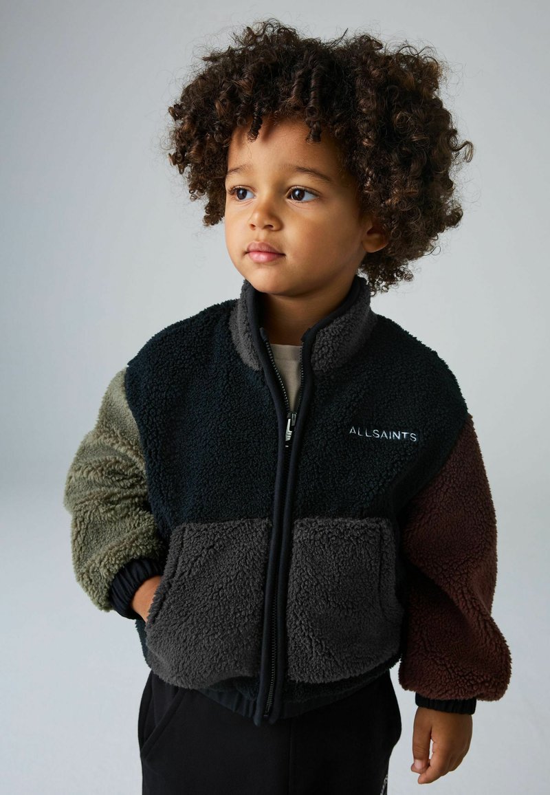 Daugiaspalvė froto striukė su užtrauktuku priekyje, turinti juodus, pilkus, alyvinius ir višninio atspalvius, tekstūruotą medžiagą ir banguotas rankogalius.