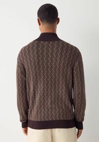 Brauner gestrickter Pullover mit geometrischem Muster, geripptem Kragen und Ärmelabschlüssen, strukturiertem Stoff und klassischer Passform.