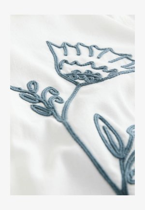 Design brodat cu flori în fir albastru pe un fundal de țesătură albă, având forme intricate de frunze și petale cu detalii texturate.