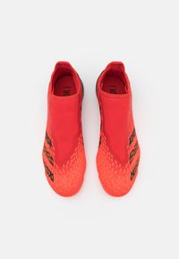 Scarpe sportive rosse senza lacci con upper in tessuto testurizzato, caratterizzate da dettagli neri e un design leggero e elasticizzato.