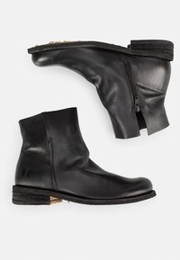 Bottines en cuir noir avec un bout arrondi, une fermeture éclair sur le côté et un petit talon empilé. Présente une finition mate et des détails de texture subtils.