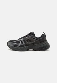 Scarpa sportiva nera realizzata con una combinazione di materiali in rete e sintetici, con accenti testurizzati e una suola spessa e imbottita con un profilo robusto.
