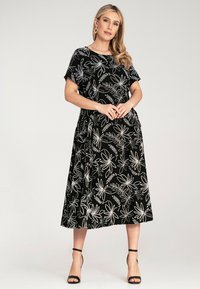 Black midi dress with white floral pattern, short sleeves, and relaxed fit. Smooth fabric with a gentle sheen and ankle-length hem.