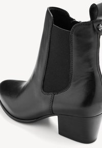 Bottine en cuir noir avec un bout arrondi, panneaux latéraux élastiques et un petit talon carré. Présente une texture lisse et de subtils détails de couture.