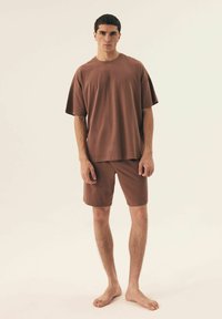 Brown cotton t-shirt with short sleeves, paired with matching knee-length shorts. Both pieces have a relaxed fit and smooth texture.