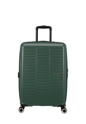 Valigia rigida verde con scanalature orizzontali, quattro ruote, maniglia nera retrattile e logo "American Tourister" sul davanti.