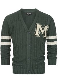 Cardigan verde a maglia con colletto a V, con un grande logo bianco "M" e due strisce orizzontali bianche sulle maniche. Cinque bottoni sul davanti.