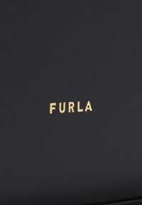 Zwart lederen textuur met een subtiele nerf. Bevat een goudkleurig reliëf "FURLA" logo in het midden.