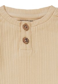 Hellbeige geripptes Oberteil mit rundem Ausschnitt, ausgestattet mit zwei braunen Knopfverschlüssen und subtiler Struktur. Markenetikett ist im Kragen sichtbar.