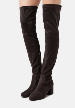 Stivali in suede marrone al ginocchio con tacco a blocco, caratterizzati da una texture liscia, cerniera laterale e dettagli cuciti lungo il bordo superiore.