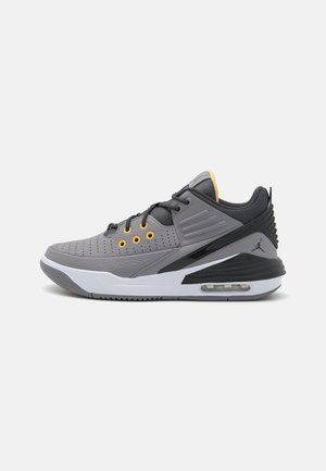 Chaussure de sport basse grise et noire avec œillets jaunes, semelle blanche, coussin d'air et logo Jumpman noir sur le talon.