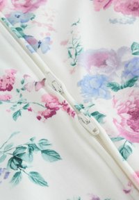 Lilleline tõmblukuga riideese, millel on roosad, lillad ja sinised lilled valgel taustal. Pehme kangas, sile tekstuur ja nähtavad tõmbluku detailid.
