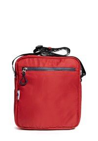 Červená čtvercová kabelka přes rameno s přední kapsou na zip, černo-bílým nastavitelným páskem a malou logovou štítkem na boku.
