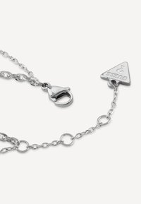 Collana in metallo argento con maglie ovali e circolari, dotata di un tag logo triangolare e una chiusura a moschettone.