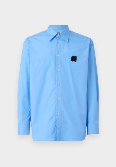 Maglietta azzurra a maniche lunghe in tessuto liscio, con colletto a punta e un logo ricamato nero sul lato sinistro del petto.