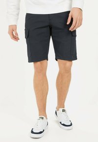 Marine cargoshorts van duurzaam katoen hebben een relaxte pasvorm, met twee zijzakken en een omgeslagen zoom. Gecombineerd met witte sneakers.