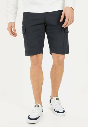 Navy cargo shorts made of durable cotton have a relaxed fit, featuring two side pockets and a folded hem. Paired with white sneakers.