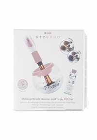 Sats för rengöring och torkning av sminkborstar i en vit låda. Inkluderar en genomskinlig, globformat rengöringsenhet, rosa detaljer och en flaska med rengöringslösning.