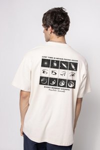 Krémové bavlnené tričko s krátkym rukávom, ktoré na zadnej strane obsahuje mriežku ilustrácií očí a text. Vo voľnom strihu a s minimálnou textúrou.