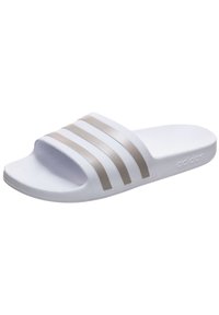 Sandale de slide blanche avec trois bandes métalliques grises sur le dessus. Fabriquée dans un matériau lisse et flexible avec une semelle texturée.