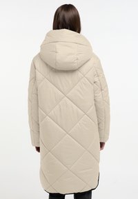 Beige gewatteerde pufferjack met een capuchon, met een lange pasvorm, diagonale stiksels en een gladde textuur. De achterkant toont ronde schouders.