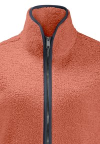 Giacca in pile corallo con collo alto, zip frontale completa e bordo blu navy. Presenta una superficie morbida e texture.
