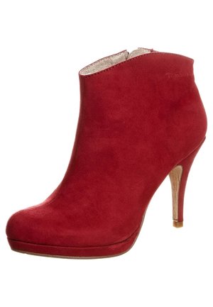 Rød ruskindsstøvle med rundt snudetip, sidelukning med lynlås og tynd høj hæl.