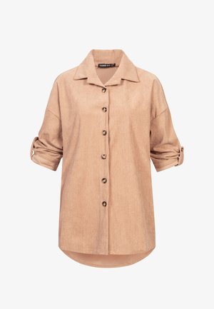 Beżowa koszula sztruksowa z kołnierzykiem, zapinana na guziki z przodu, z podwiniętymi rękawami. Posiada pionowe prążkowanie oraz zaokrąglony dół z nieco dłuższym tyłem.