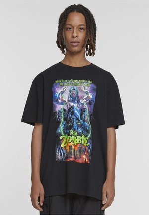 Άτομο με dreadlocks φοράει μαύρο μπλουζάκι Rob Zombie με γραφικά που απεικονίζουν ζόμπι, αστραπές και αστικό τοπίο με κείμενο πάνω και κάτω.