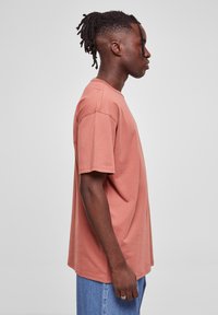 Tricou cu mânecă scurtă, culori roz prăfuit, din bumbac, cu o croială lejeră și tiv drept. Textură netedă.
