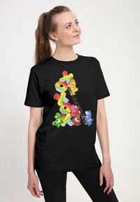 Černé tričko s barevnými kreslenými medv�ědy v různých barvách, jak šplhají po žebříku, s jasnou, živou grafikou a hravým designem.