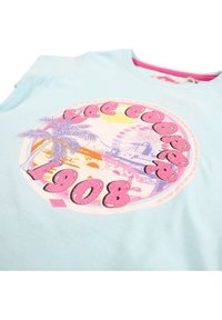 T-shirt bleu clair avec un graphique rond représentant des palmiers et une grande roue, agrémenté d'un texte pailleté rose indiquant "1908".