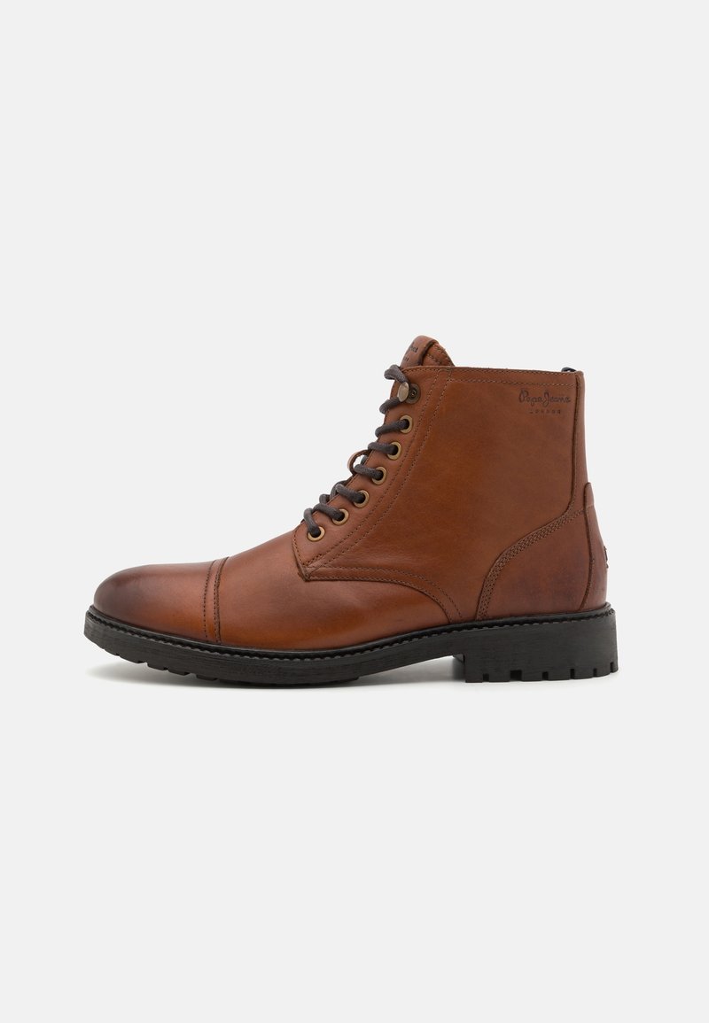 Bottine montante en cuir marron à lacets avec semelle noire, détails de surpiqûres et nom de la marque embossé sur le côté.