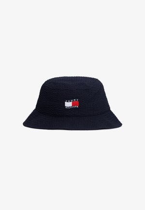 Sombrero tipo bucket azul marino con textura y un parche cosido del logo de Tommy Hilfiger en el centro frontal, con colores rojo, blanco y azul marino.