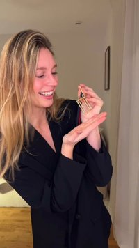 Accessoire de porte-clés en or de forme rectangulaire, avec une enveloppe transparente. Tenue par une personne sur un fond neutre.