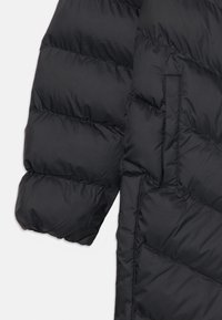 Μαύρο μπουφάν με πούπουλα που διαθέτει σχεδίαση με καπιτονέ και απαλή, λεία υφή. Περιλαμβάνει πλαινές τσέπες και φαρδύ, επενδεδυμένο μανίκι.