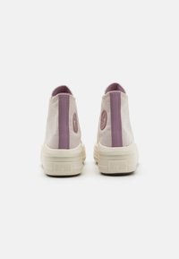 High-top sneakers in light beige canvas with a purple stripe and rubber soles. Features a star logo and textured heel.