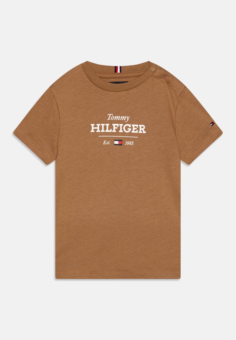 Ruda medvilninė marškinė su trumpomis rankovėmis, ant kurių yra balta užrašas "Tommy HILFIGER" ir logotipas. Apvalus iškirpimas ir mažas logotipo akcentas ant rankovės.
