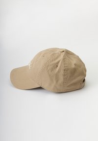 Beige pamut baseball sapka ívelt karimával, hímzett felirattal elöl, hatszögletű dizájnnal és szellőző lyukakkal.