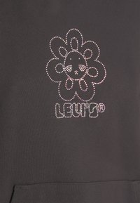 Felpa nera con un design a fiori impreziosito da gemme e il testo "LEVI'S" sottostante in cristalli coordinati. Tessuto dalla superficie liscia.