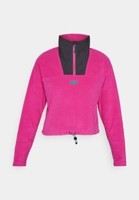 Polaire à enfiler de couleur rose vif avec un col montant noir et une fermeture éclair à mi-longueur. Dispose d'un ourlet à cordon de serrage et d'un petit logo turquoise.